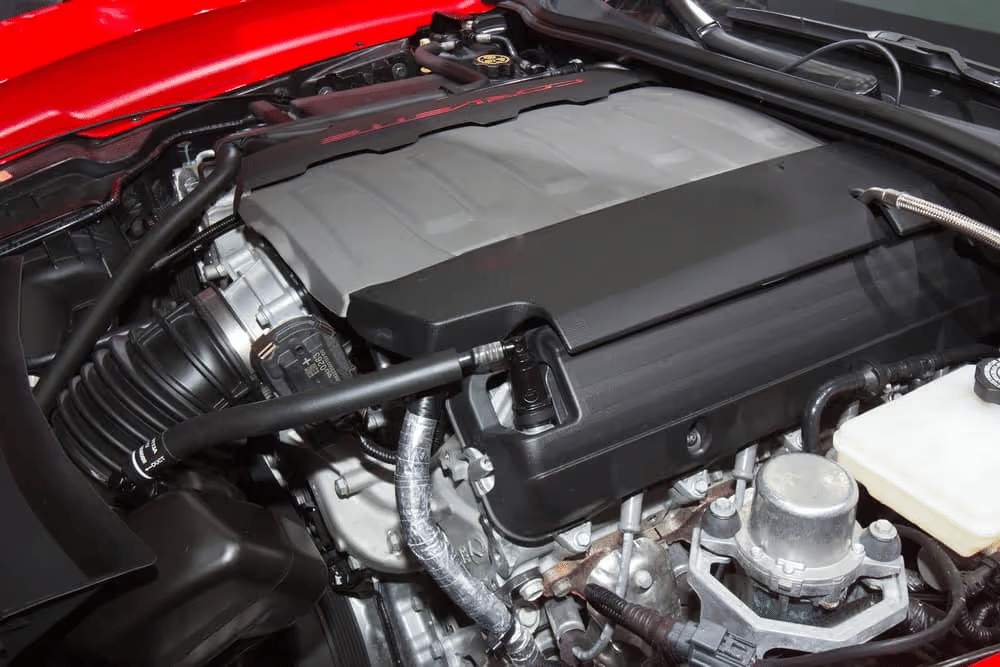 Close-up of a high-performance car engine under a red hood, highlighting detailed components.