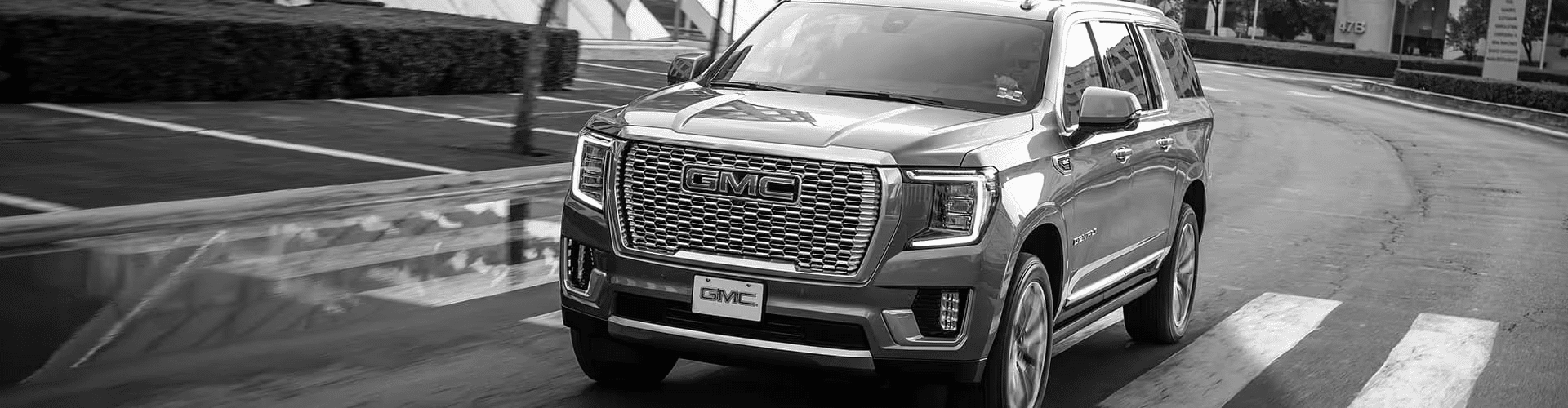 GMC SUV driving on a city road, highlighting luxury design and powerful performance.