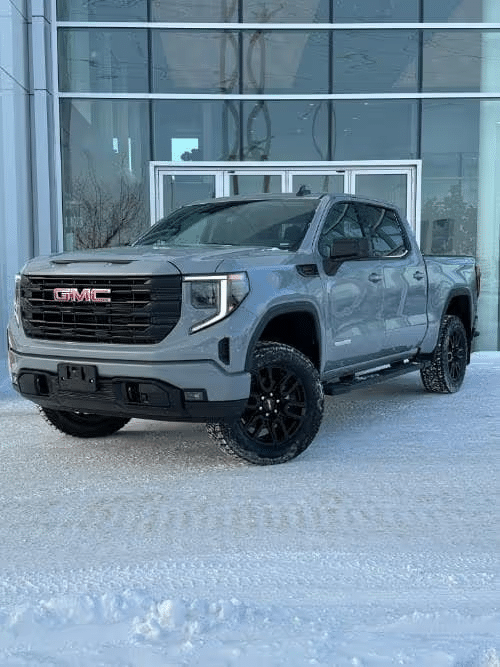 GMC pickup truck parked in front of modern glass building on snowy ground.