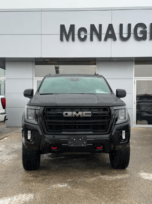Black GMC SUV parked at dealership, showcasing bold grille and modern design.