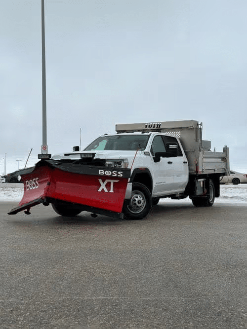 Truck with BOSS XT snowplow parked on a snowy road, ready for snow removal.