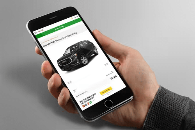 Person viewing 2020 GMC Terrain for sale on a smartphone, price visible; online car shopping concept.