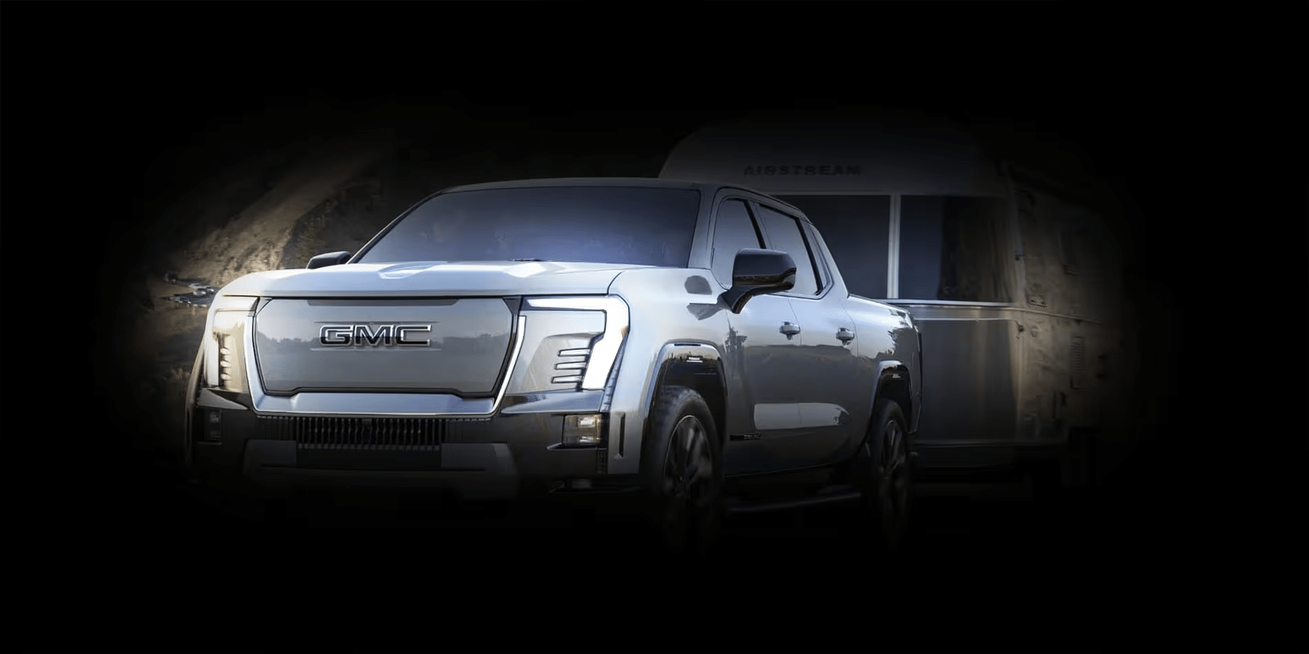 Electric GMC truck towing an Airstream trailer in low-light conditions.