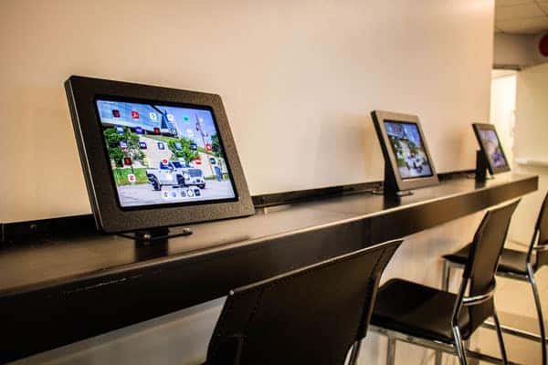 Tablets mounted on a sleek counter in a modern workspace, emphasizing technology integration.