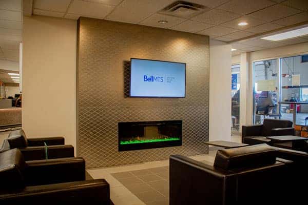 Modern waiting area with leather chairs, a wall-mounted TV, and an electric fireplace, creating a cozy atmosphere.