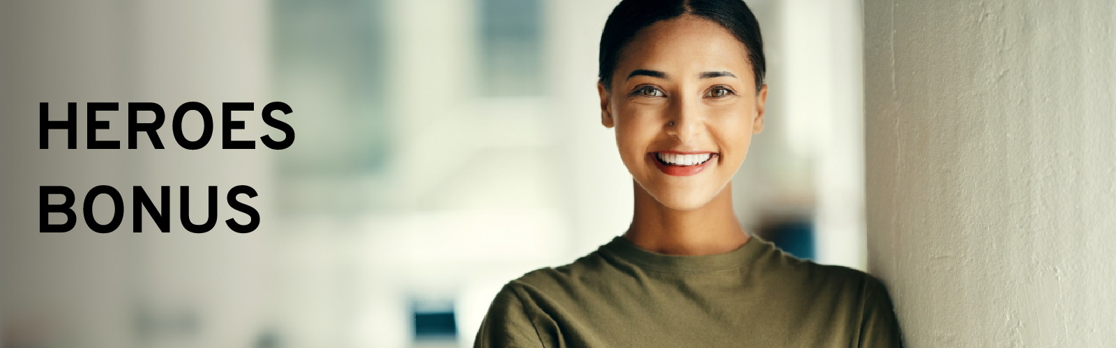 Smiling woman in a green shirt next to "Heroes Bonus" text on a blurred background.