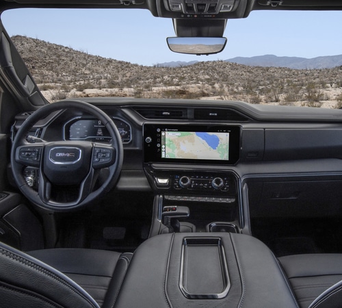 Modern SUV cabin with sleek dashboard, infotainment screen showing navigation, and desert view outside.