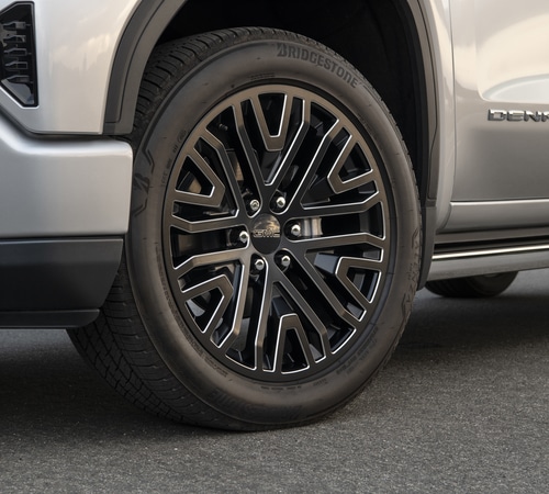 Close-up of a car's black alloy wheel with intricate design on a Bridgestone tire.