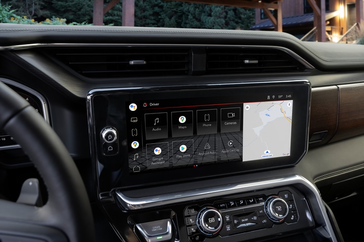 The image shows the interior of a modern car, featuring a steering wheel, a digital dashboard, and a large touchscreen display on the center console. The display shows various controls and settings. The car has a sleek, black design.