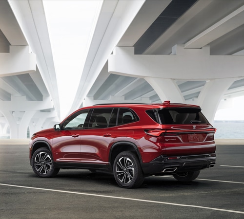 Red SUV parked under modern bridge with sleek design and elegant curves.
