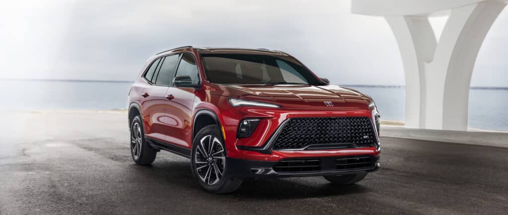 Red SUV parked by a coastal road, showcasing sleek design and modern features.