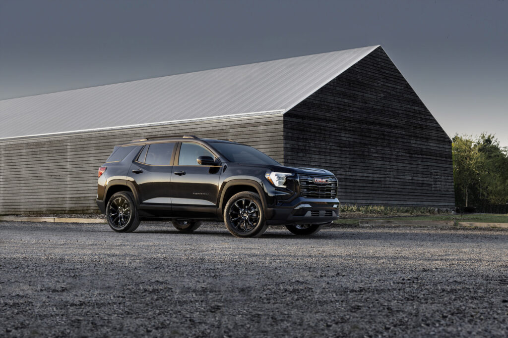 Black SUV parked in front of a large wooden barn, under a cloudy sky, showcasing the vehicle's design.
