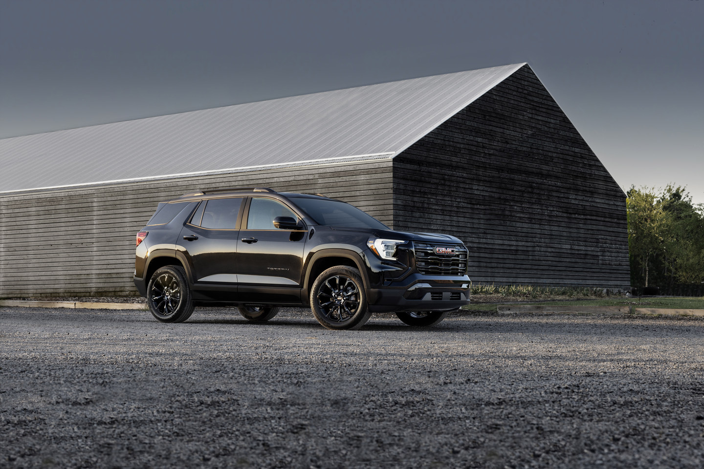Black SUV parked in front of a large wooden barn, under a cloudy sky, showcasing the vehicle's design.