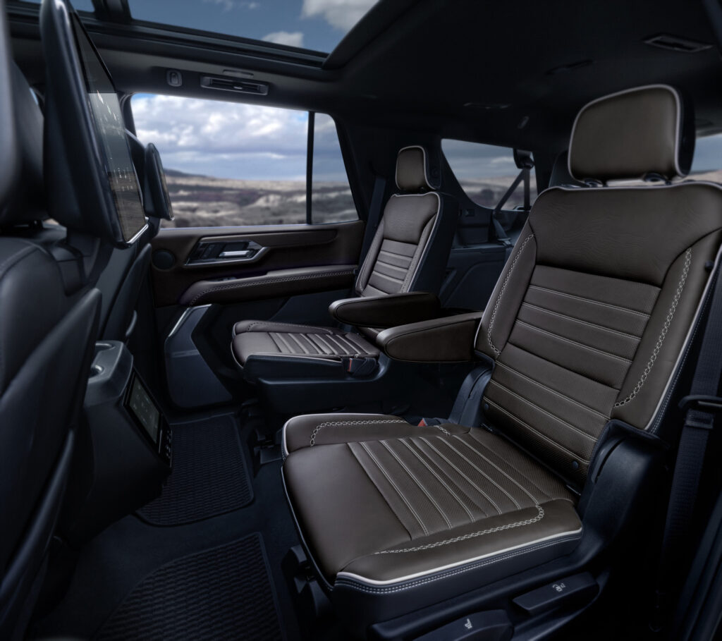 Luxurious SUV interior with brown leather seats, ample legroom, and panoramic window view.