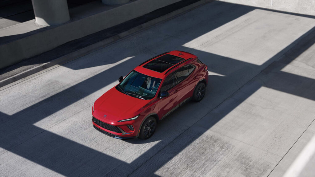 Red SUV parked in a sunlit urban setting, highlighting its sleek design and modern features.